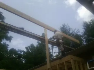 Carpenter setting a ridge beam over a new addition frame — Ice Dam Removal by Roofing Brothers in Panama City