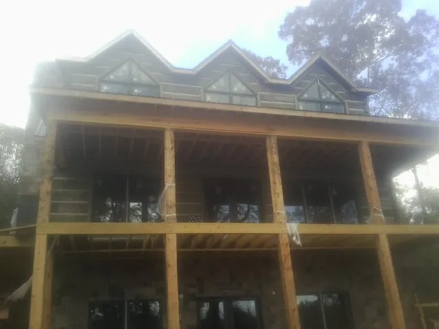 Dormers and porch framing on a large log home under construction — Roof Coating work by our crew in Panama City