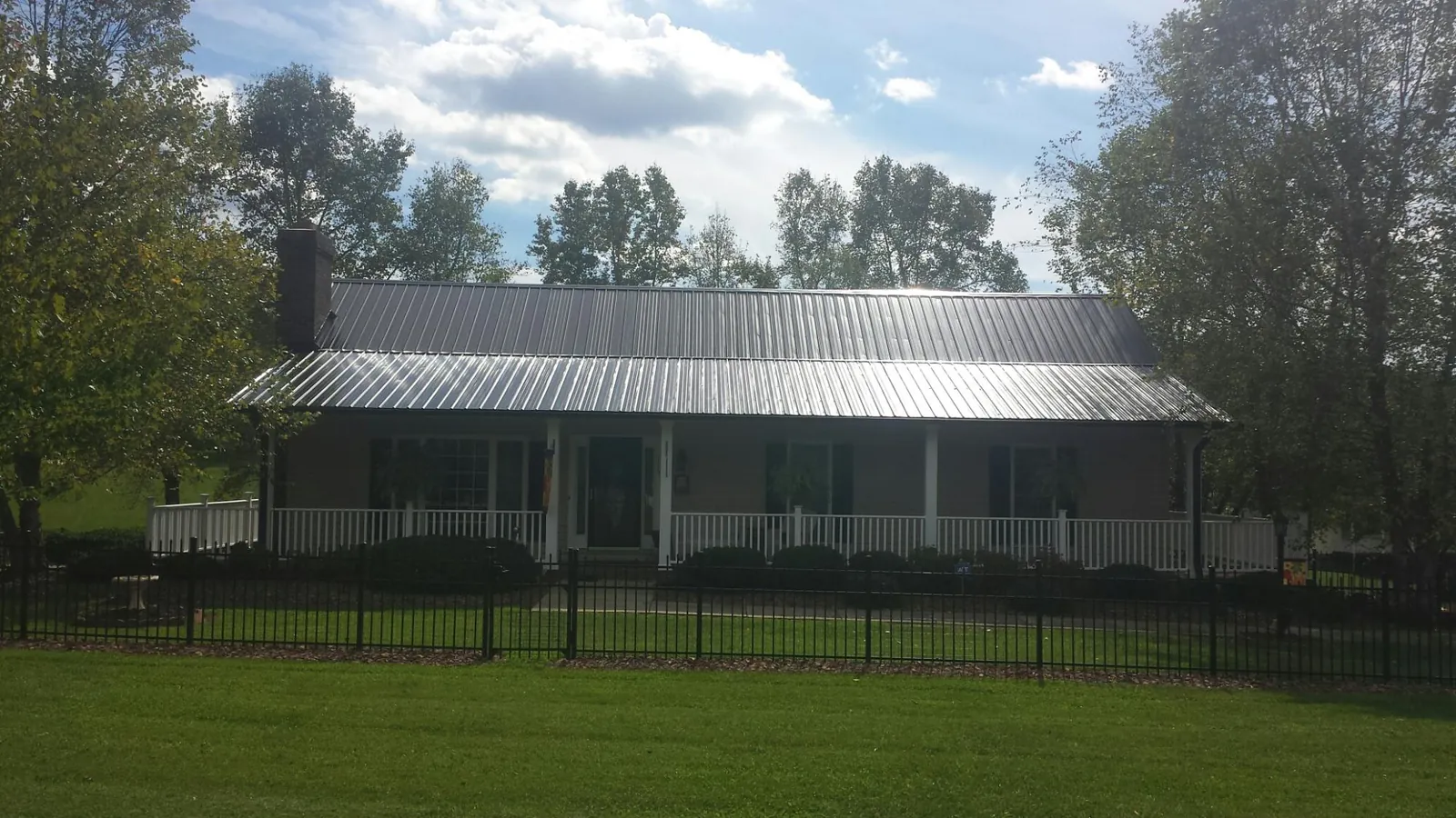 Gray metal roof on a brick ranch with a full width front porch — Gutter Guard Installation work by our crew in Panama City