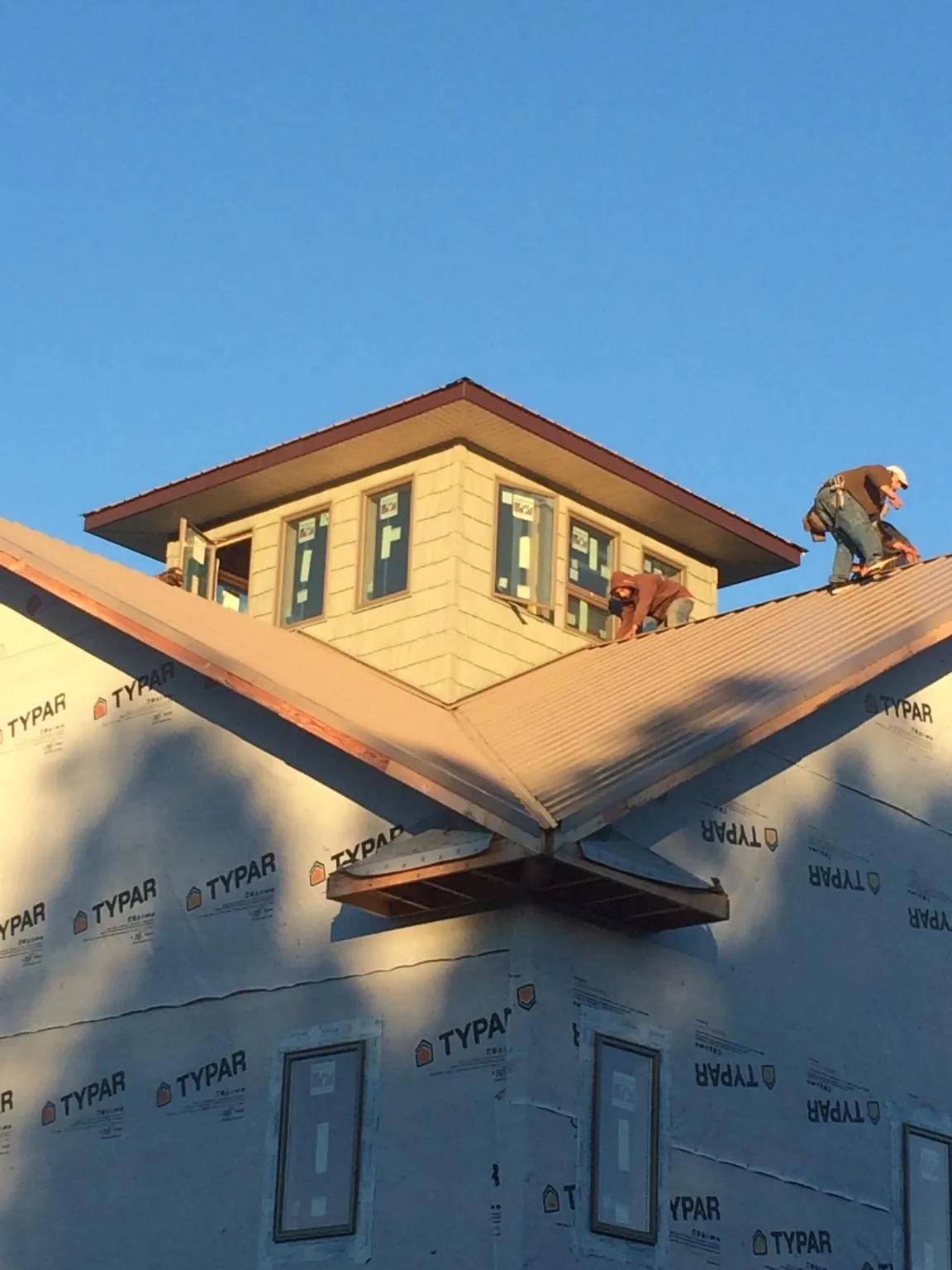 Roofers working around a rooftop cupola on a new metal roof at sunset — Roof Waterproofing in Panama City by Roofing Brothers
